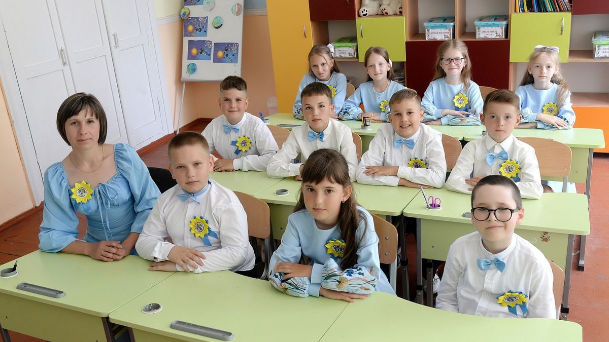 A classroom of children in blue and white uniforms seated with their teacher.